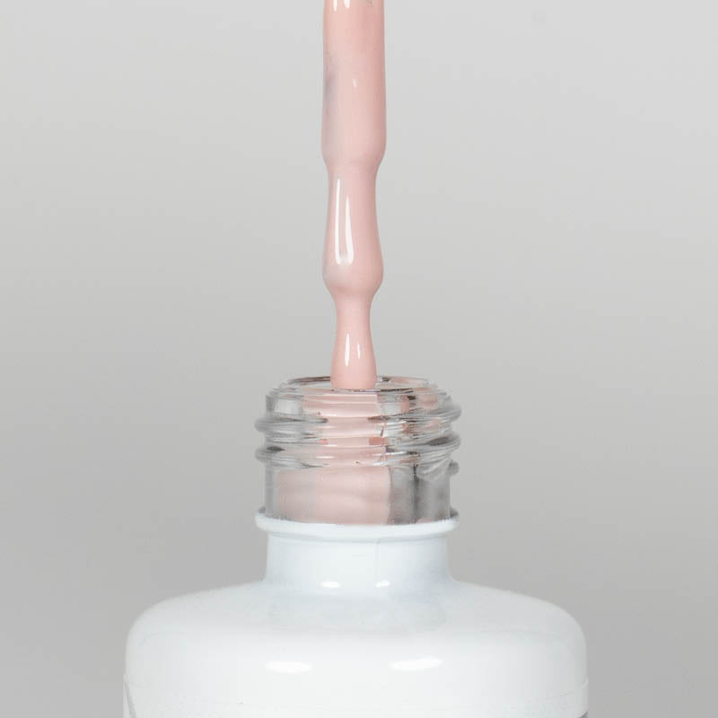 Nahaufnahme einer offenen Longlife UV-Lack Mademoiselle Flasche. Die Farbe ist ein helles Nude. Der UV-Nagellack tropft am Pinsel herunter.