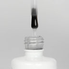 Nahaufnahme einer offenen Longlife UV-Lack Make it Matt Flasche. Die Farbe ist transparent doch leicht milchig. Der UV-Nagellack tropft am Pinsel herunter.