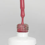 Nahaufnahme einer offenen Longlife UV-Lack Malta Rose Flasche. Die Farbe ist ein dunkles Rosa. Der UV-Nagellack tropft am Pinsel herunter.
