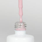 Nahaufnahme einer offenen Longlife UV-Lack Mellow Rose Flasche. Die Farbe ist ein helles Rosa mit niedriger Sättigung. Der UV-Nagellack tropft am Pinsel herunter.