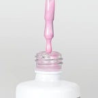 Nahaufnahme einer offenen Longlife UV-Lack Metallic Bonbon Pretty in Pink Flasche. Die Farbe ist ein helles Rosa mit Metallic-Effekt. Der UV-Lack tropft am Pinsel herunter.
