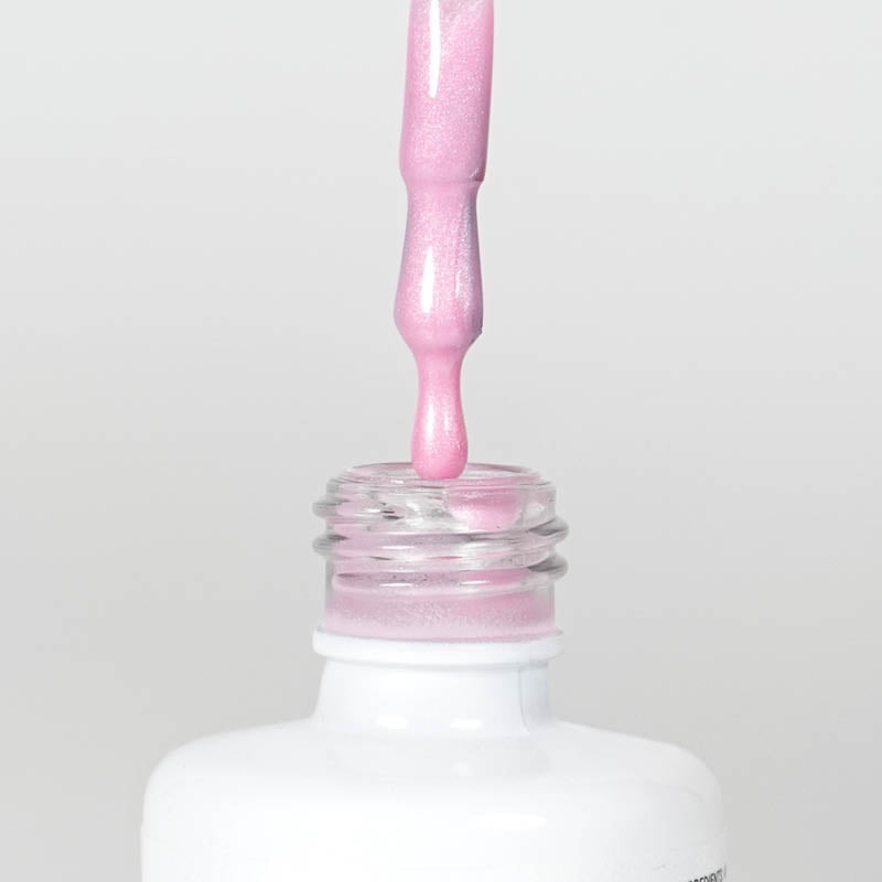 Nahaufnahme einer offenen Longlife UV-Lack Metallic Bonbon Pretty in Pink Flasche. Die Farbe ist ein helles Rosa mit Metallic-Effekt. Der UV-Lack tropft am Pinsel herunter.