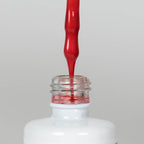 Nahaufnahme einer offenen Longlife UV-Lack Metallic Melon Flasche. Die Farbe ist ein intensives Rot mit Metallic-Effekt. Der UV-Lack tropft am Pinsel herunter.