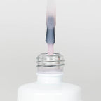 Nahaufnahme einer Longlife UV-Lack Top Gloss Milky Rose Flasche. Die Farbe ist ein leicht deckendes Rosa. Der UV-Lack tropft am Pinsel herunter.