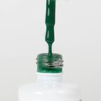 Nahaufnahme einer Longlife UV-Lack Flasche der Farbe Ultramarine Green. Die Farbe ist ein dunkles Grün mit hoher Sättigung. Der UV-Lack tropft am Pinsel herunter.