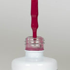 Nahaufnahme einer Longlife UV-Lack Flasche der Farbe Viva Magenta. Die Farbe ist ein knalliges, dunkles Pink mit leichtem Rotstich. Der UV-Lack tropft am Pinsel herunter.