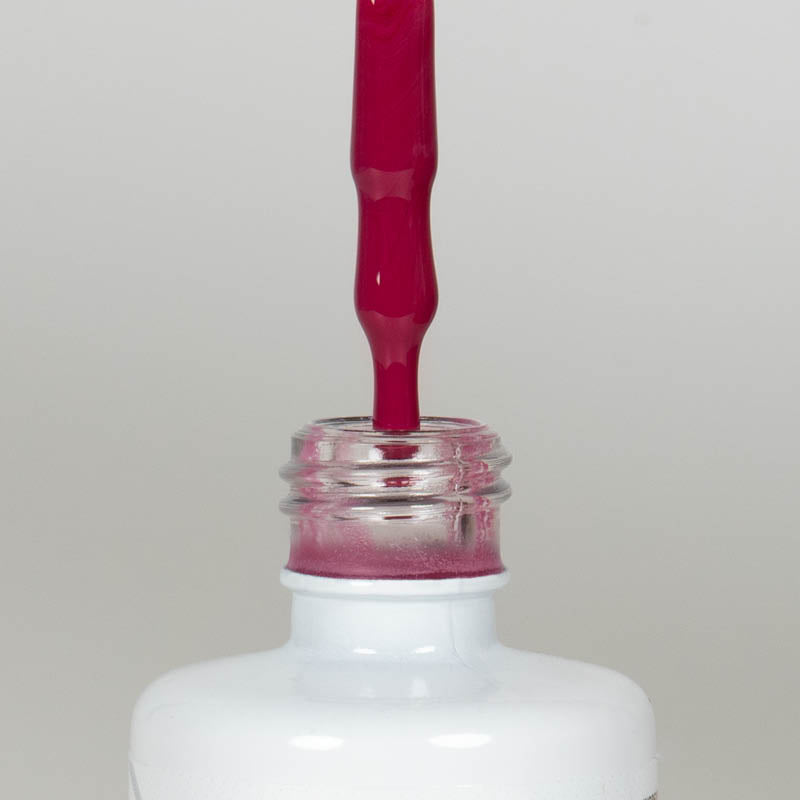 Nahaufnahme einer Longlife UV-Lack Flasche der Farbe Viva Magenta. Die Farbe ist ein knalliges, dunkles Pink mit leichtem Rotstich. Der UV-Lack tropft am Pinsel herunter.