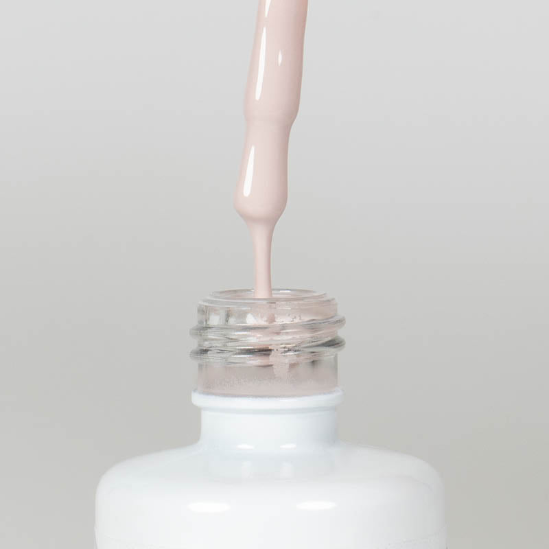 Nahaufnahme einer Longlife UV-Lack Flasche der Farbe Wellbeing. Die Farbe ist ein helles Nude. Der UV-Lack tropft am Pinsel herunter.