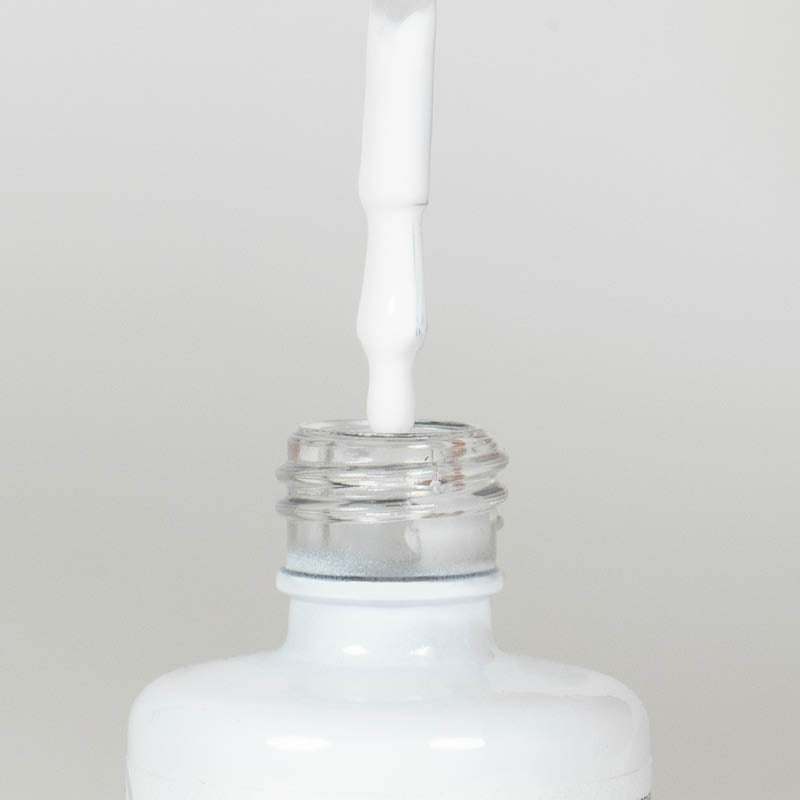 Nahaufnahme einer Longlife UV-Lack Flasche der Farbe White. Die Farbe ist ein hochdeckendes Weiß. Der UV-Lack tropft am Pinsel herunter.