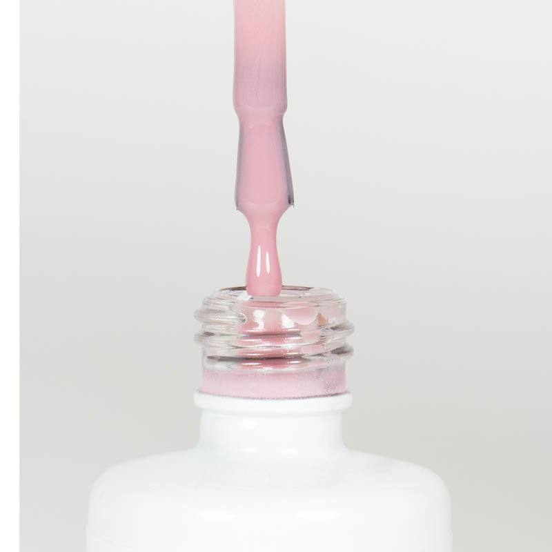Nahaufnahme einer offenen Longlife UV-Lack Natural Rose Flasche. Die Farbe ist ein helles Rosa mit hoher Sättigung. Der UV-Lack tropft am Pinsel herunter.