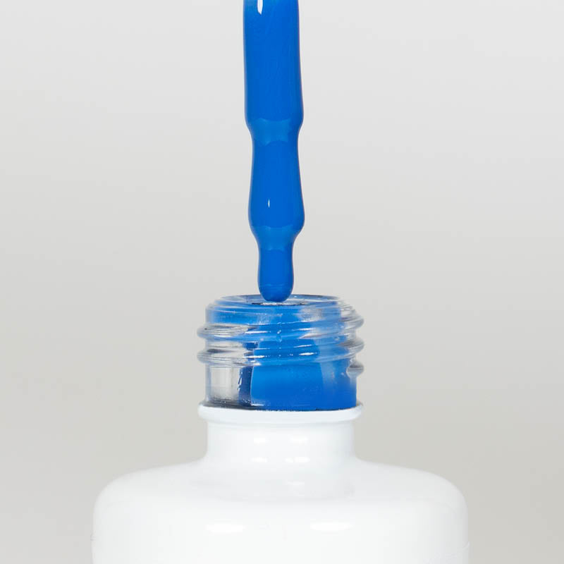 Nahaufnahme einer offenen Longlife UV-Lack Nebulas Blue Flasche. Die Farbe ist ein knalliges Blau mit hoher Sättigung. Der UV-Nagellack tropft am Pinsel herunter.