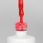 Nahaufnahme einer offenen Longlife UV-Lack Neon Cyclam Flasche. Die Farbe ist ein knalliges Pink mit Rot-Stich mit hoher Sättigung. Der UV-Lack tropft am Pinsel herunter.