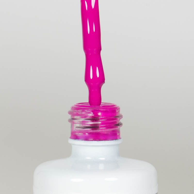 Nahaufnahme einer offenen Longlife UV-Lack Neon Fuchsia Flasche. Die Farbe ist ein knalliges Pink mit Violett-Stich mit hoher Sättigung. Der UV-Lack tropft am Pinsel herunter.