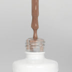 Nahaufnahme einer offenen Longlife UV-Lack Nude Flasche. Die Farbe ist ein warmer Nude-Ton mit hoher Sättigung. Der UV-Lack tropft am Pinsel herunter.