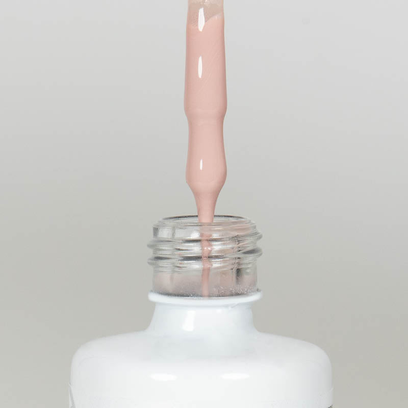 Nahaufnahme einer offenen Longlife UV-Lack Pale Dogwood Flasche. Die Farbe ist ein helles Nude mit hoher Sättigung. Der UV-Lack tropft am Pinsel herunter.
