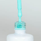 Nahaufnahme einer offenen Longlife UV-Lack Palma Flasche. Die Farbe ist ein knalliges helles Türkis mit hoher Sättigung. Der UV-Lack tropft am Pinsel herunter.