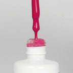 Nahaufnahme einer offenen Longlife UV-Lack Pink Peacock Flasche. Die Farbe ist ein knalliges dunkles Pink mit hoher Sättigung. Der UV-Lack tropft am Pinsel herunter.