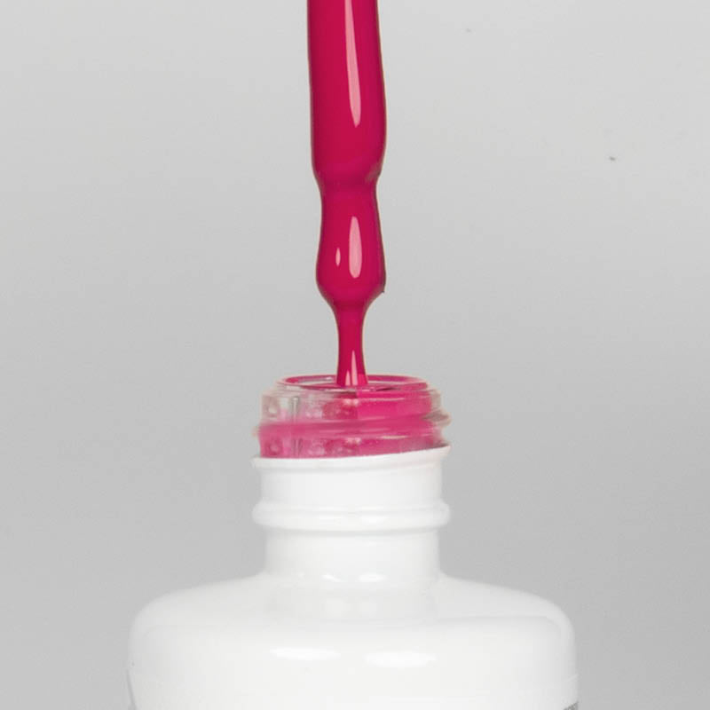 Nahaufnahme einer offenen Longlife UV-Lack Pink Peacock Flasche. Die Farbe ist ein knalliges dunkles Pink mit hoher Sättigung. Der UV-Lack tropft am Pinsel herunter.