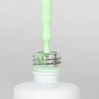 Nahaufnahme einer offenen Longlife UV-Lack Pistachio Flasche. Die Farbe ist ein sehr helles Grün. Der UV-Lack tropft am Pinsel herunter.