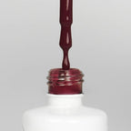 Nahaufnahme einer offenen Longlife UV-Lack Purple Grapes Flasche. Die Farbe ist ein dunkles Rot mit Pink-Violett-Stich. Der UV-Lack tropft am Pinsel herunter.