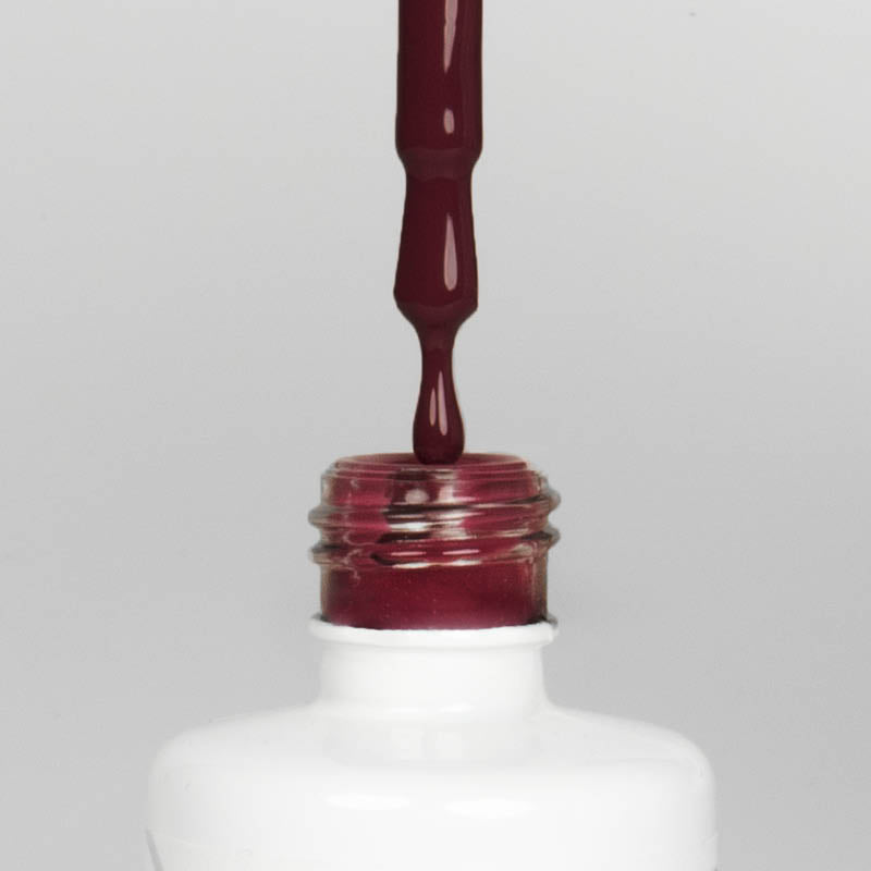 Nahaufnahme einer offenen Longlife UV-Lack Purple Grapes Flasche. Die Farbe ist ein dunkles Rot mit Pink-Violett-Stich. Der UV-Lack tropft am Pinsel herunter.
