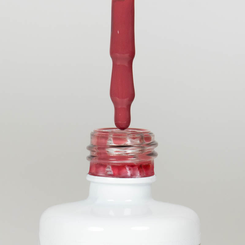 Nahaufnahme einer offenen Longlife UV-Lack Rapture Rose Flasche. Die Farbe ist ein dunkles Rosa mit Orange-Stich und niedriger Sättigung. Der UV-Lack tropft am Pinsel herunter.