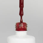 Nahaufnahme einer offenen Longlife UV-Lack Red Chestnut Flasche. Die Farbe ist ein dunkles Rot. Der UV-Lack tropft am Pinsel herunter.