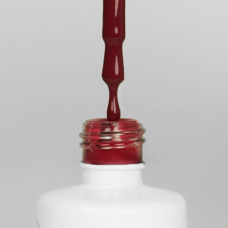 Nahaufnahme einer offenen Longlife UV-Lack Red Chestnut Flasche. Die Farbe ist ein dunkles Rot. Der UV-Lack tropft am Pinsel herunter.