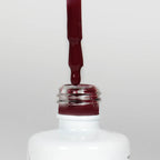 Nahaufnahme einer offenen Longlife UV-Lack Red Pear Flasche. Die Farbe ist ein dunkles Rot. Der UV-Lack tropft am Pinsel herunter.