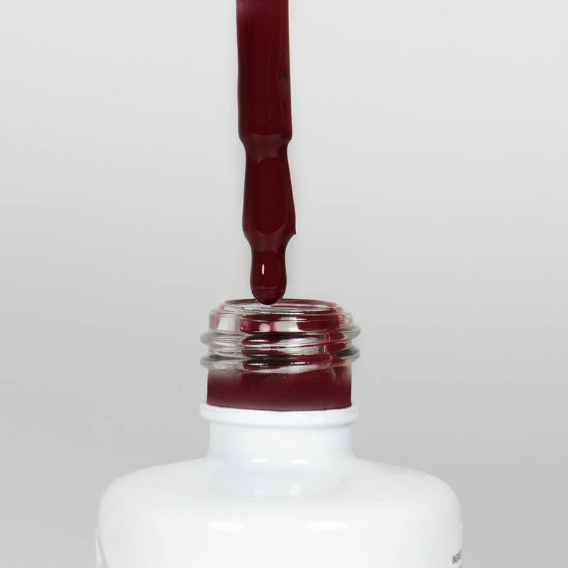 Nahaufnahme einer offenen Longlife UV-Lack Red Pear Flasche. Die Farbe ist ein dunkles Rot. Der UV-Lack tropft am Pinsel herunter.