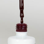 Nahaufnahme einer offenen Longlife UV-Lack Rouge Noir Flasche. Die Farbe ist ein dunkles Rot mit leichtem Braunstich. Der UV-Lack tropft am Pinsel herunter.