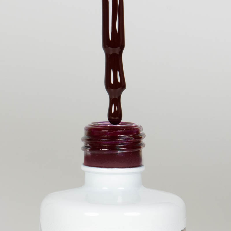 Nahaufnahme einer offenen Longlife UV-Lack Rouge Noir Flasche. Die Farbe ist ein dunkles Rot mit leichtem Braunstich. Der UV-Lack tropft am Pinsel herunter.