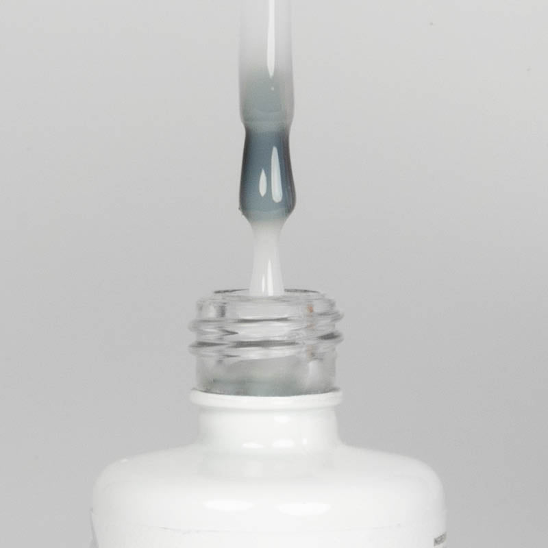 Nahaufnahme einer Longlife UV-Lack Rubber Base Milky White Flasche. Die Farbe ist durchscheinend Weiß. Der UV-Lack tropft am Pinsel herunter.