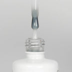 Nahaufnahme einer Longlife UV-Lack Rubber Base Milky White Flasche. Die Farbe ist durchscheinend Weiß. Der UV-Lack tropft am Pinsel herunter.