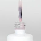 Nahaufnahme einer Longlife UV-Lack Rubber Base Cover Flasche. Die Farbe ist durchscheinend Rosa. Der UV-Lack tropft am Pinsel herunter.