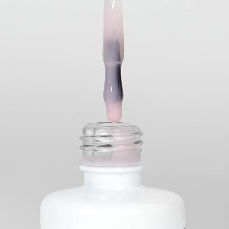Nahaufnahme einer Longlife UV-Lack Rubber Base Cover Flasche. Die Farbe ist durchscheinend Rosa. Der UV-Lack tropft am Pinsel herunter.
