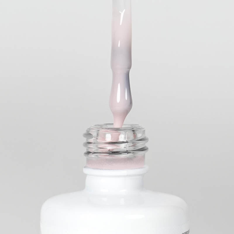 Nahaufnahme einer Longlife UV-Lack Rubber Base Cover One Flasche. Die Farbe ist durchscheinend Rosa. Der UV-Lack tropft am Pinsel herunter.