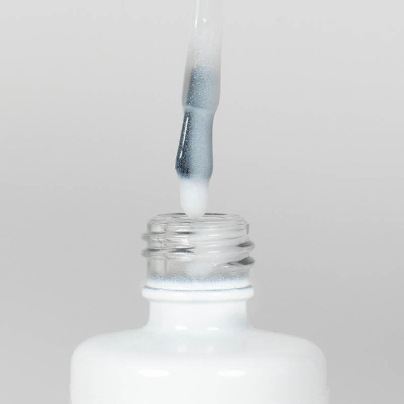Nahaufnahme einer Longlife UV-Lack Rubber Base Cover Pearl White Flasche. Die Farbe ist durchscheinend Weiß mit Perl-Effekt. Der UV-Lack tropft am Pinsel herunter.