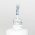 Nahaufnahme einer Longlife UV-Lack Rubber Base Cover Sparkling White Flasche. Die Farbe ist durchscheinend Weiß mit Glitzereffekt. Der UV-Lack tropft am Pinsel herunter.