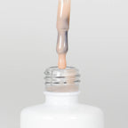 Nahaufnahme einer Longlife UV-Lack Rubber Base Cover Three Flasche. Die Farbe ist durchscheinend Nude mit Orange-Stich. Der UV-Lack tropft am Pinsel herunter.