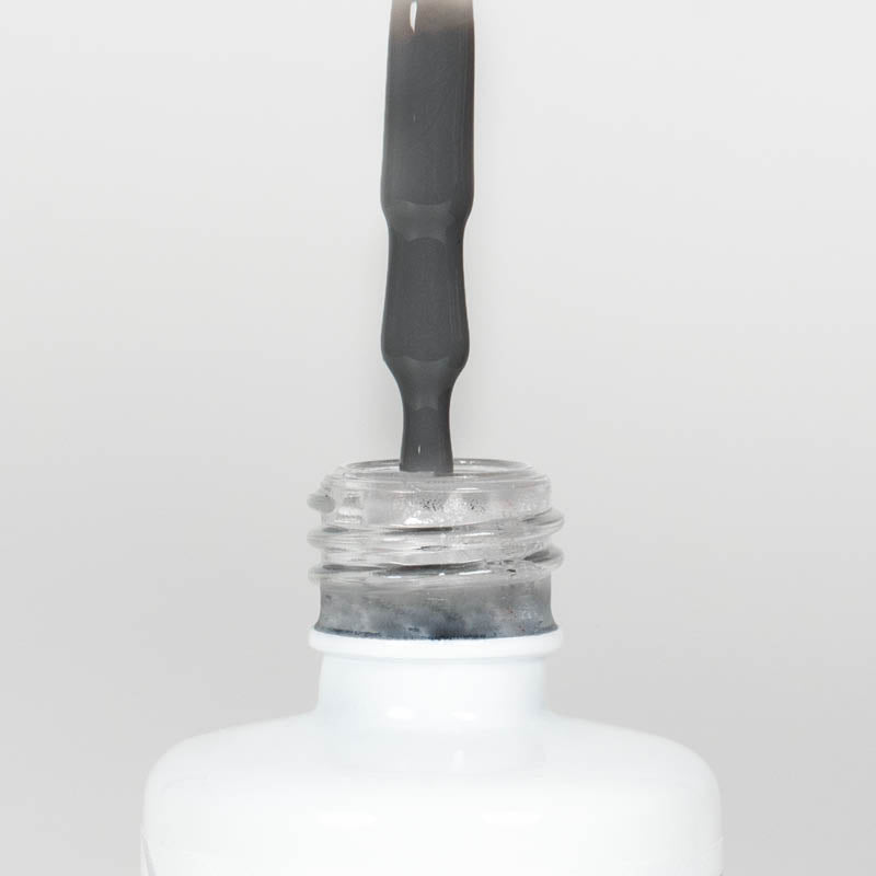 Nahaufnahme einer Longlife UV-Lack Sharkskin Flasche. Die Farbe ist Dunkelgrau. Der UV-Lack tropft am Pinsel herunter.