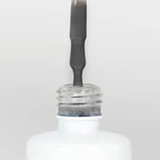 Nahaufnahme einer Longlife UV-Lack Sharkskin Flasche. Die Farbe ist Dunkelgrau. Der UV-Lack tropft am Pinsel herunter.