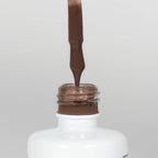 Nahaufnahme einer Longlife UV-Lack Slurry Flasche. Die Farbe ist dunkelbraun. Der UV-Lack tropft am Pinsel herunter.