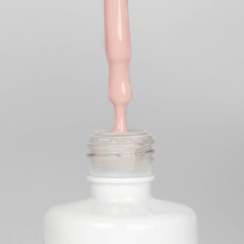 Nahaufnahme einer Longlife UV-Lack Soul Flasche. Die Farbe ist ein helles Nude mit leichtem Pinkstich. Der UV-Lack tropft am Pinsel herunter.