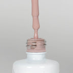 Nahaufnahme einer Longlife UV-Lack Spirit Flasche. Die Farbe ist ein helles Nude. Der UV-Lack tropft am Pinsel herunter.