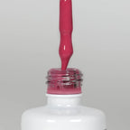 Nahaufnahme einer Longlife UV-Lack Strawberry Flasche. Die Farbe ist Pink mit leichtem Rotstich. Der UV-Lack tropft am Pinsel herunter.