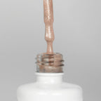 Nahaufnahme einer offenen Longlife UV-Lack Bella Christina Flasche. Die Farbe ist ein Nude mit Glitzer Effekt. Der UV-Nagellack tropft am Pinsel herunter.