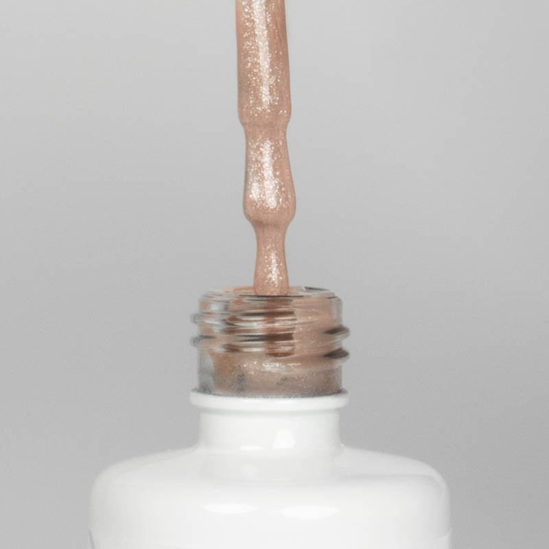 Nahaufnahme einer offenen Longlife UV-Lack Bella Christina Flasche. Die Farbe ist ein Nude mit Glitzer Effekt. Der UV-Nagellack tropft am Pinsel herunter.