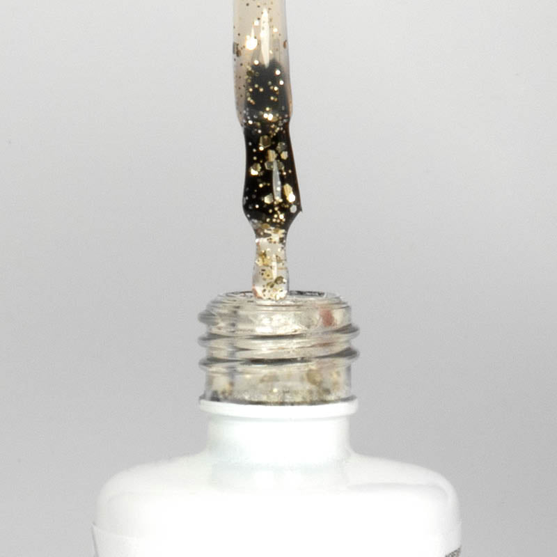 Nahaufnahme einer offenen Longlife UV-Lack Egg Shell Shiny Gold Flasche. Die Farbe ist transparent mit goldenen Partikeln. Der UV-Nagellack tropft am Pinsel herunter.