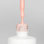 Nahaufnahme einer offenen Longlife UV-Lack Meringue Flasche. Die Farbe ist ein helles Orange-Nude mit hoher Sättigung. Der UV-Nagellack tropft am Pinsel herunter.